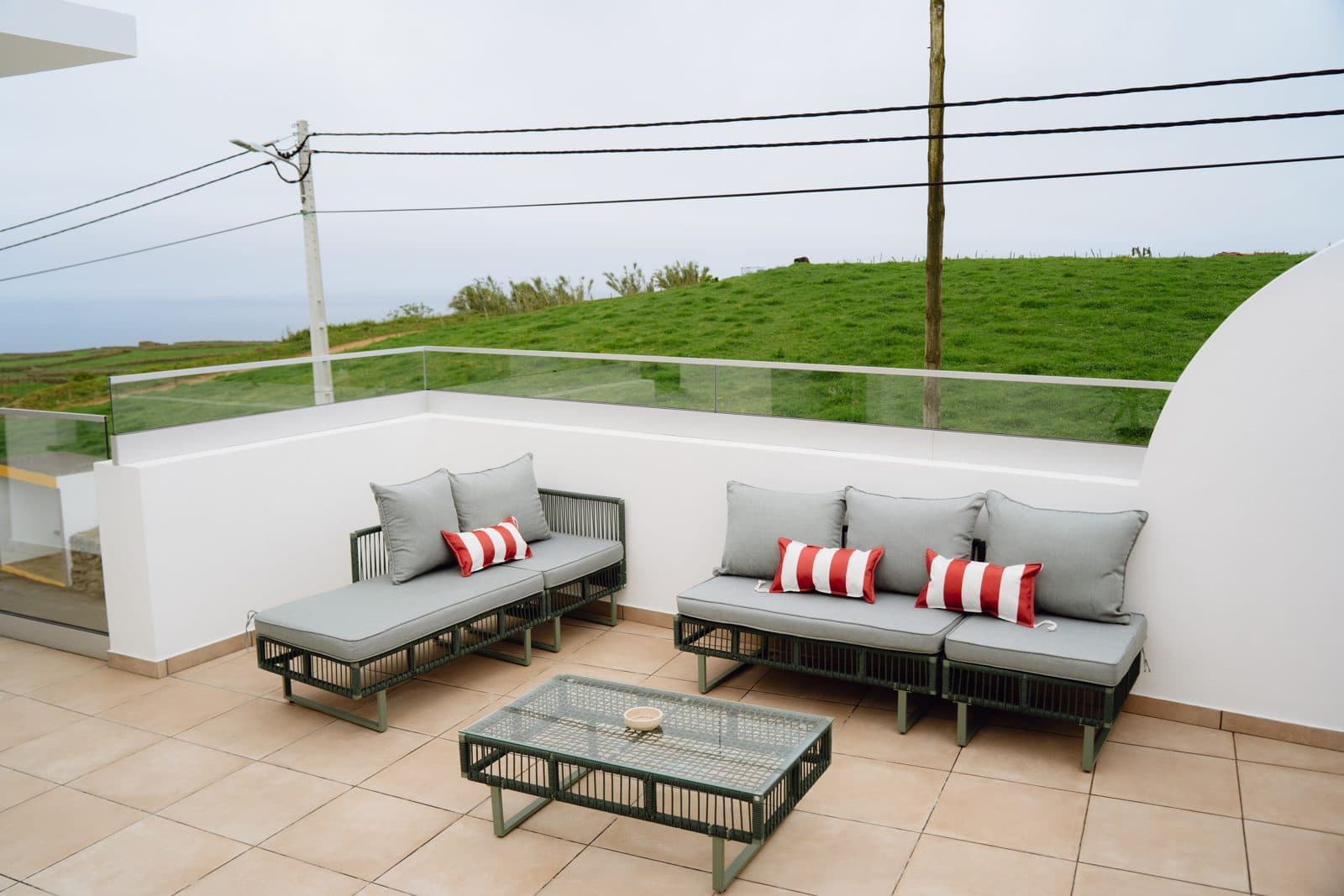Terraço do Terrassi Villa: bancada exterior com lava-loiça e remate em azulejo verde, três bancos altos de verga, e forno de lenha em tijolo com arco e lenha empilhada por baixo da bancada — vista 2